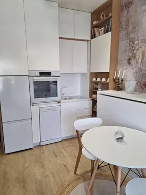 a kitchen with white cabinets and a white table at Kupidon in Dobra Voda
