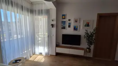 a living room with a television and a large window at Kupidon in Dobra Voda