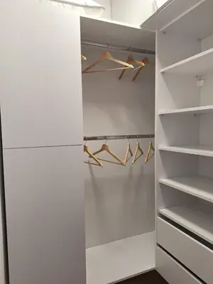 a walk in closet with white walls and wooden hangers at Kupidon in Dobra Voda