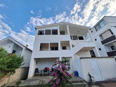 a white building with a tree in front of it at Aldina Apartments in Ulcinj