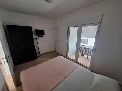 a bedroom with a bed and a balcony with a table at Aldina Apartments in Ulcinj
