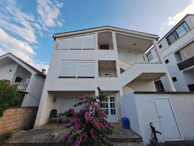 a white building with a tree in front of it at Aldina Apartments in Ulcinj