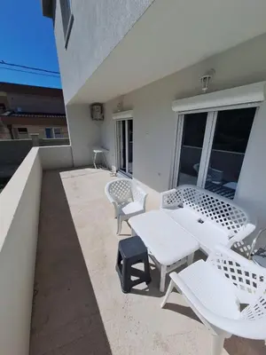 a patio with white tables and chairs on a balcony at Family house Grbalj in Kotor