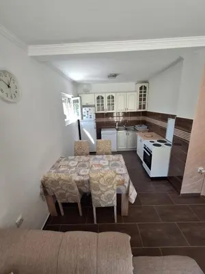 a kitchen with a table with chairs and a kitchen with white cabinets at Family house Grbalj in Kotor