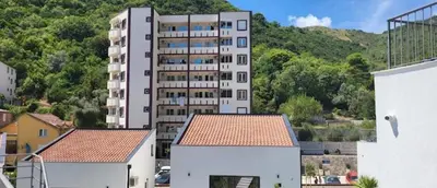 a tall white apartment building in front of a mountain at Dale apartment Becici- Paradiso in Budva
