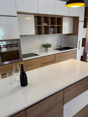 a kitchen with a white counter with a bottle and a wine glass at Garden House in Budva