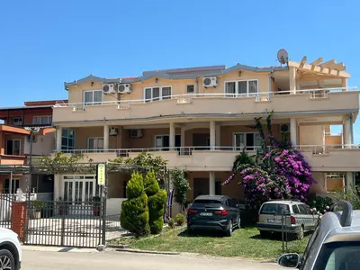 a large building with cars parked in front of it at Villa Pelinku in Ulcinj