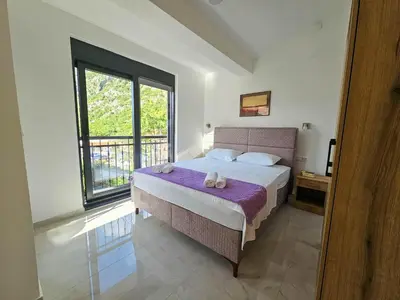 a bedroom with a bed and a large window at Harmony Garden Apartments in Kotor
