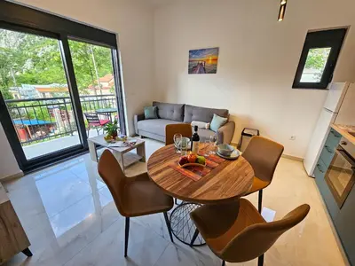 a living room with a wooden table and chairs at Harmony Garden Apartments in Kotor