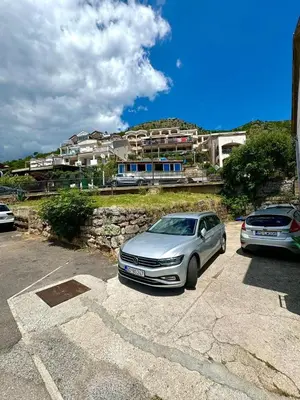 two cars parked in a parking lot in front of a building at Lenny One bedroom Apartment Sveti Stefan in Budva