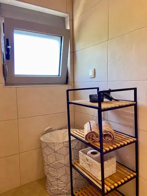 a bathroom with a shelf with towels and a window at Apartment Victor in Kotor