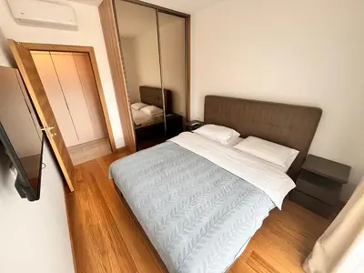 a bedroom with a large bed and a mirror at New City Luxury Apartments in Podgorica