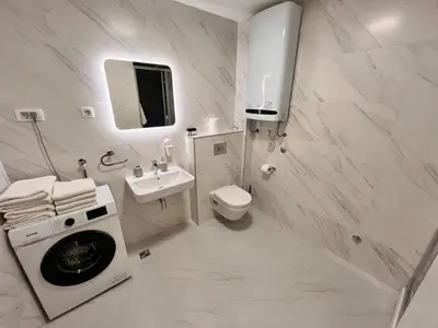 a white bathroom with a washing machine and a sink at New City Luxury Apartments in Podgorica