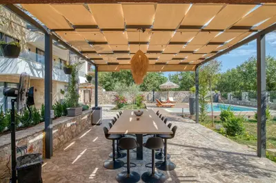 a wooden pergola with a table and chairs on a patio at VILLA Amfora in Budva