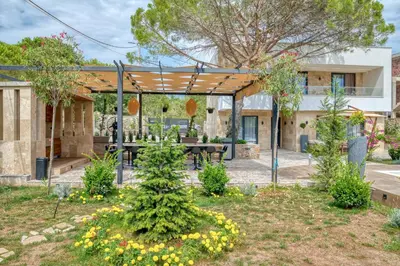 a garden with a wooden pergola and a picnic table at VILLA Amfora in Budva
