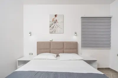 a bedroom with a large bed with white sheets at Sunset Marina in Bar