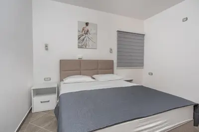 a white bedroom with a large bed and a window at Sunset Marina in Bar