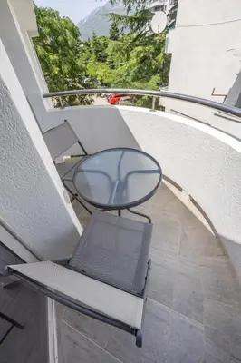 a glass table and a chair on a balcony at Sunset Marina in Bar
