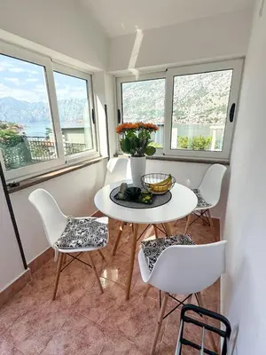 a dining room with a table and chairs and windows at Apartment Melody in Kotor