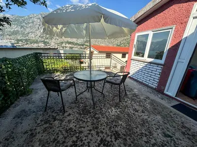 a table with two chairs and an umbrella on a patio at Apartment Melody in Kotor