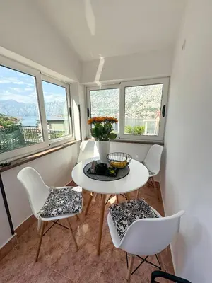a room with a table and chairs and windows at Apartment Melody in Kotor