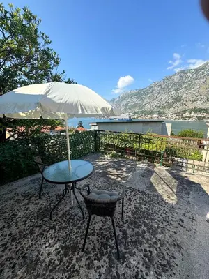 a table and chair with an umbrella on a patio at Apartment Melody in Kotor