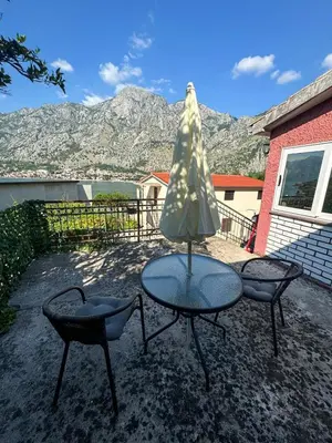 a table and two chairs and an umbrella on a patio at Apartment Melody in Kotor