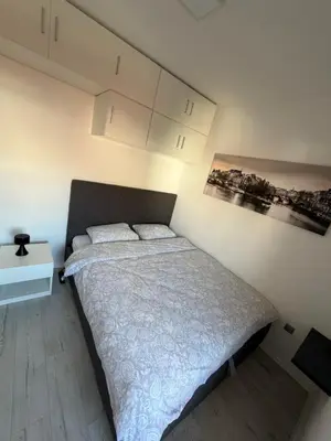 a bedroom with a bed with a white bedspread and a table at Apartment Saint Tropez Budva, Privatna garaža in Budva