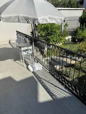 a bench with an umbrella next to a fence at Apartman Ela Podgorica in Podgorica