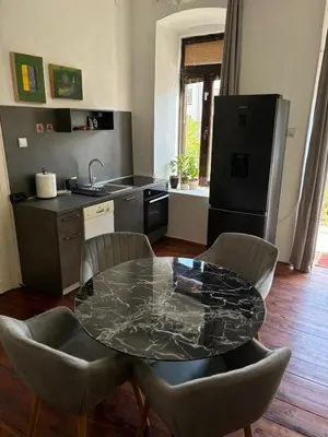 a kitchen with a table and chairs and a refrigerator at Apartman Ela Podgorica in Podgorica