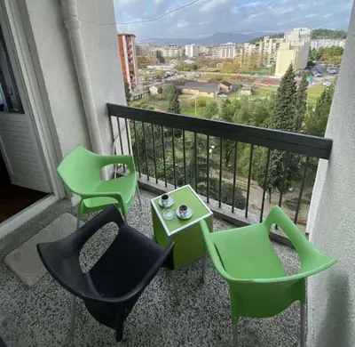 a balcony with two green chairs and a table at Tea apartment in Podgorica