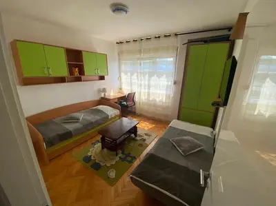 a bedroom with green cabinets and a bed and a table at Tea apartment in Podgorica
