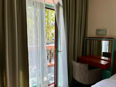 a bedroom with a sliding glass door with a desk and a window at Central 25 in Podgorica