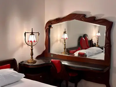 a mirror in a bedroom with a bed and a lamp at Central 25 in Podgorica