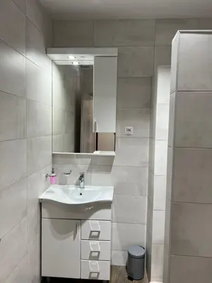 a white bathroom with a sink and a mirror at Apartmani Mareta in Petrovac na Moru