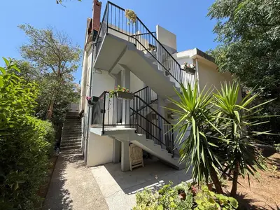 a building with stairs and a balcony with plants at Apartmani Mareta in Petrovac na Moru