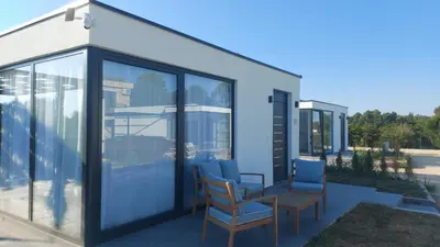 a house with glass doors and chairs on a patio at Casa Aurelia in Gornji Štoj