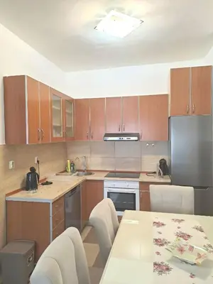 a kitchen with wooden cabinets and a table with chairs at N&B Apartment Kotor in Kotor