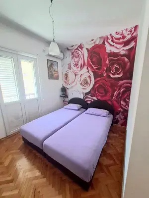 a bedroom with a bed with roses on the wall at N&B Apartment Kotor in Kotor
