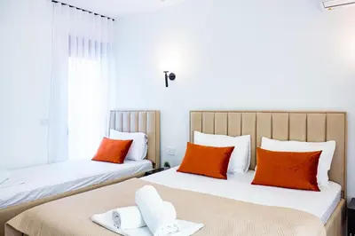 two beds in a room with orange and white pillows at Riian Luxury Apartments in Ulcinj