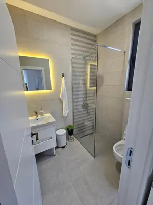 a bathroom with a shower and a sink and a toilet at La Vida Apartments in Babalonija