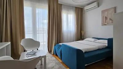 a bedroom with a blue bed and a window at White Sensation in Podgorica