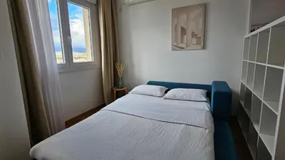 a small bedroom with a blue bed and a window at White Sensation in Podgorica
