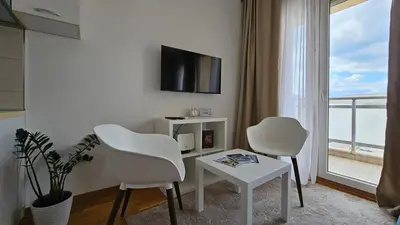 a living room with two white chairs and a tv at White Sensation in Podgorica