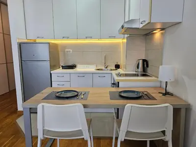 a kitchen with a table and two white chairs at White Sensation in Podgorica