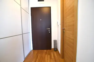 a hallway with a brown door and a wooden floor at White Sensation in Podgorica