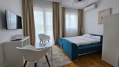a bedroom with a blue bed and a white chair at White Sensation in Podgorica