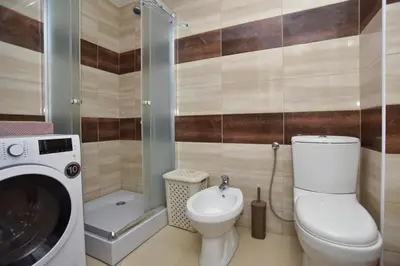 a bathroom with a toilet and a washing machine at Petra Apartment in Ulcinj