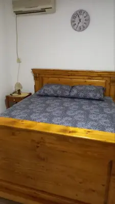 a bedroom with a wooden bed with a clock on the wall at Milica, Soba sa kupatilom in Petrovac na Moru