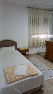 a bedroom with a bed and a table and a window at Milica, Soba sa kupatilom in Petrovac na Moru